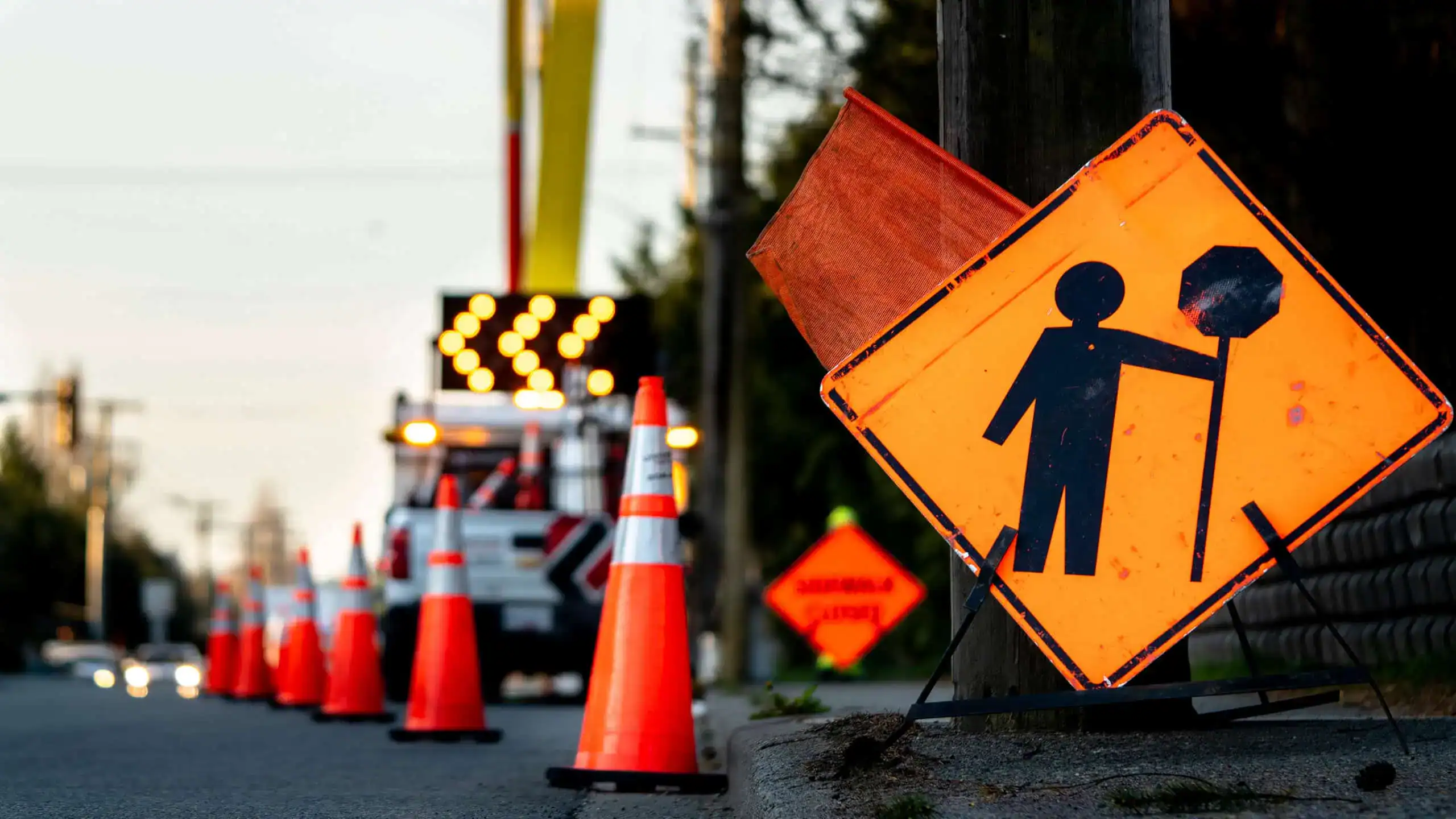 Confusion road work sign with traffic cones and repair vehicle on the street, indicating construction zone safety.